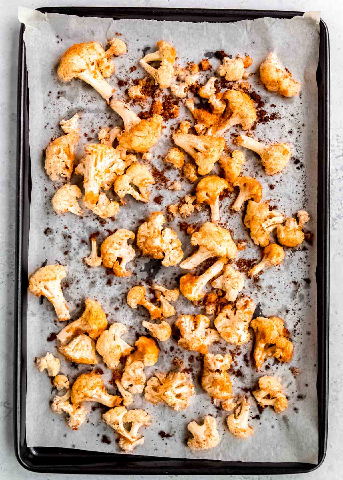 overhead image of baked cauliflower spread on a baking sheet