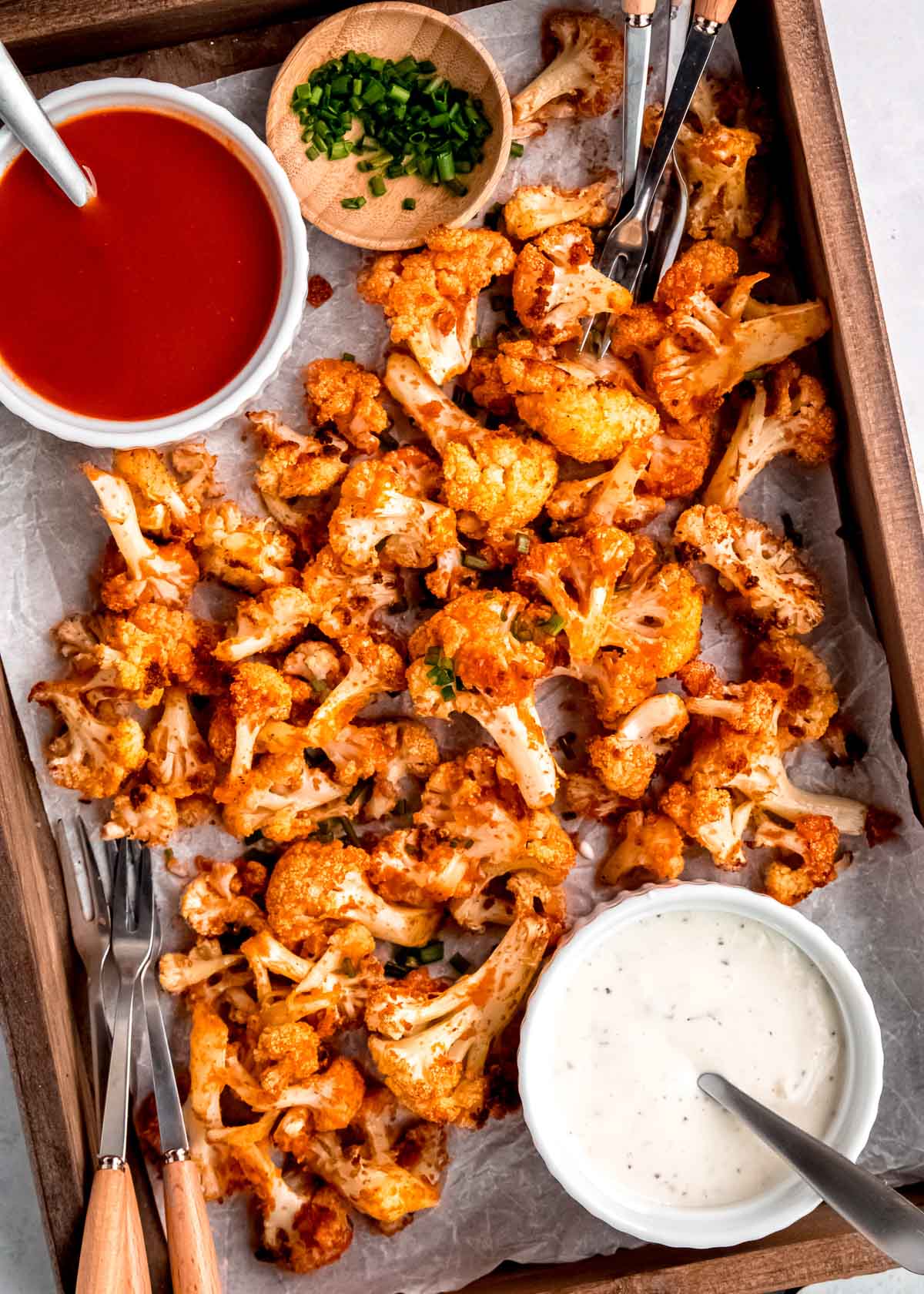 overhead image of buffalo cauliflower and dipping sauce on a sheet pan