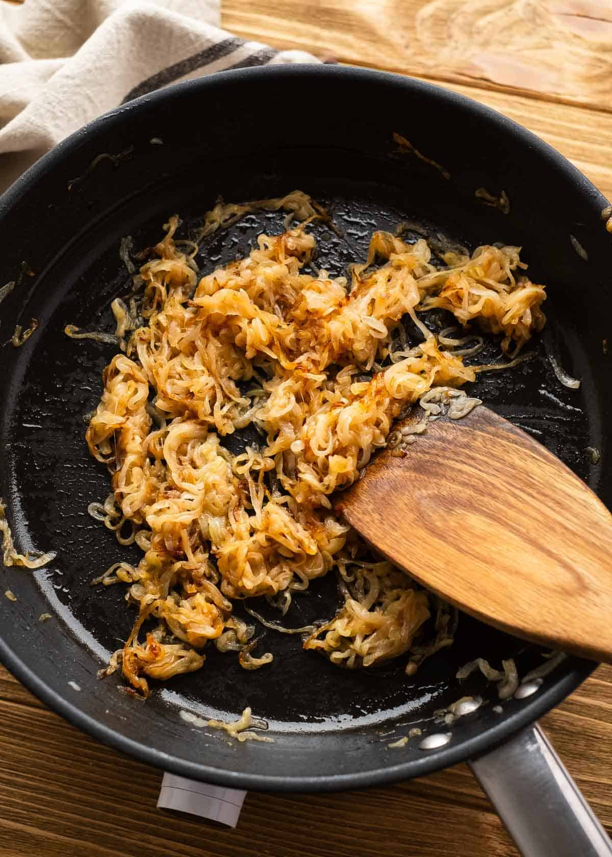 overhead shot of caramelized white onions being stirred in a cast iron skillet 