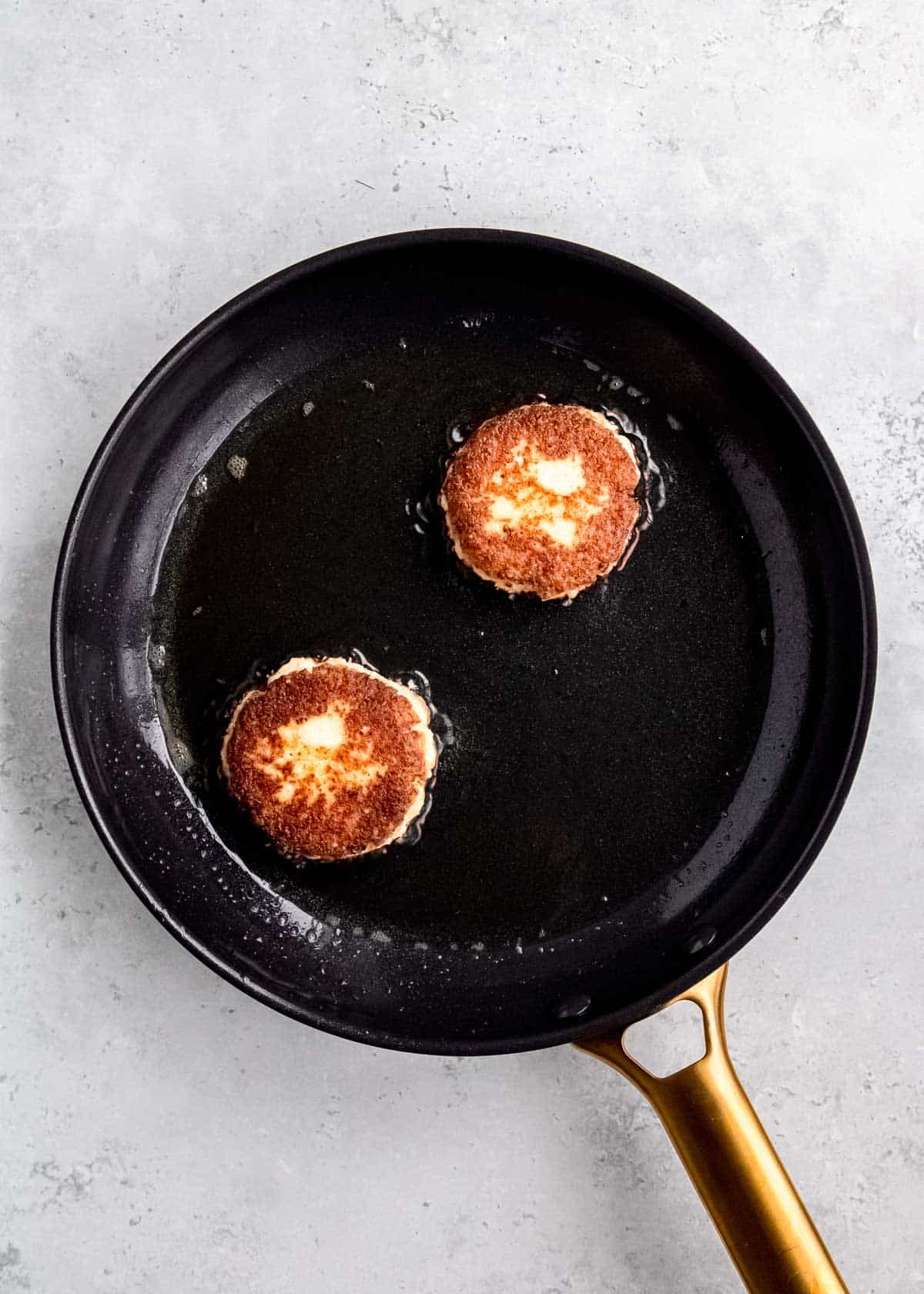 an overhead shot of cooked cauliflower fritters in a skillet