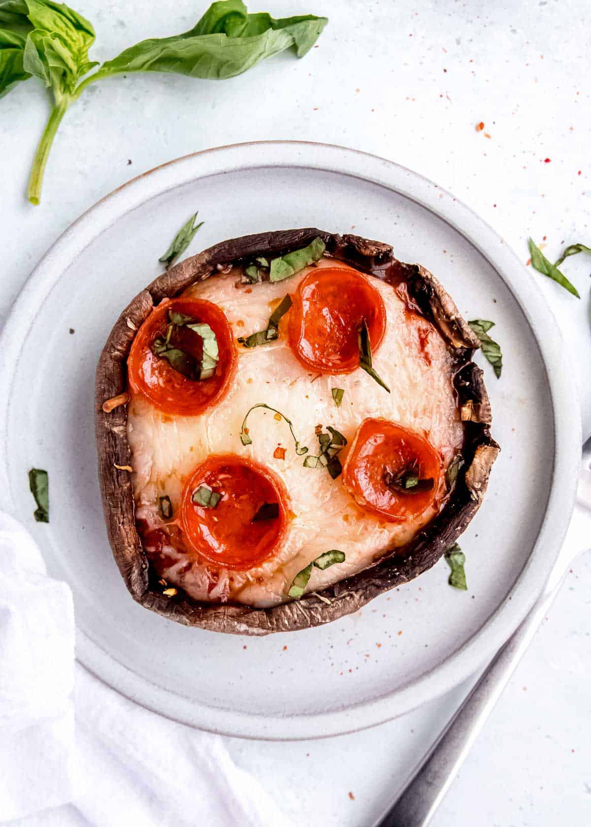 pepperoni pizza stuffed mushroom sprinkled with chopped basil on a plate