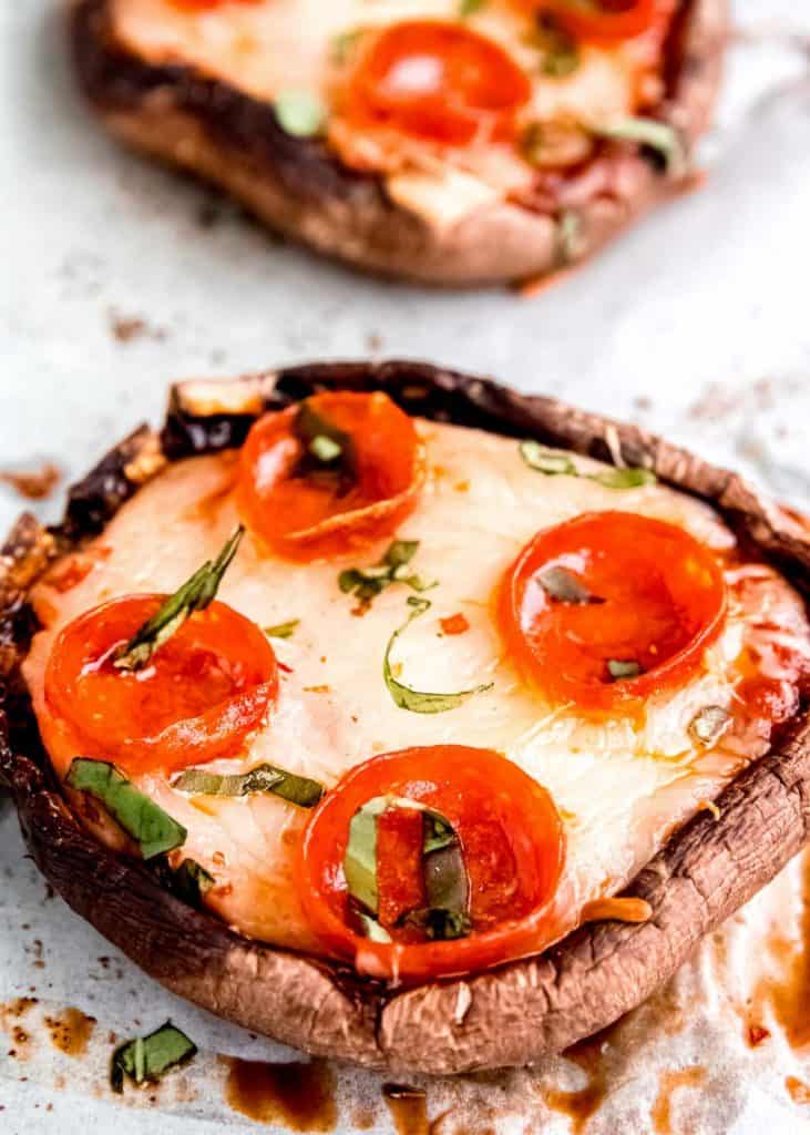 two pepperoni pizza portobellos on a piece of parchment paper