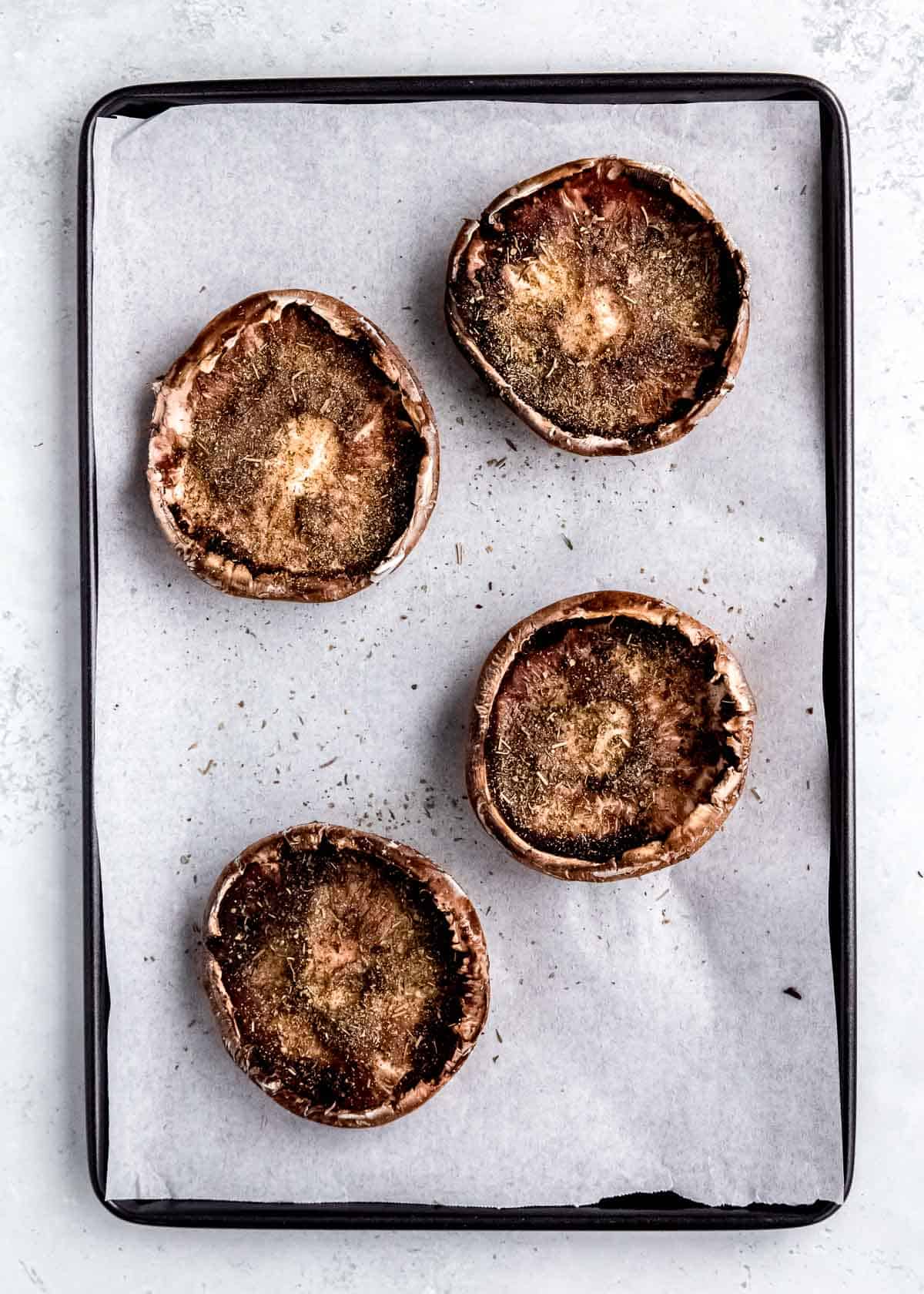 seasoning being added to mushrooms on white background 