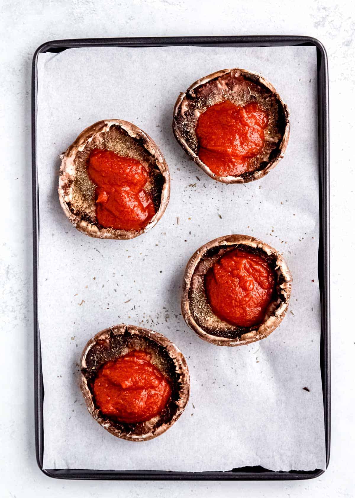 pizza sauce being added to mushrooms