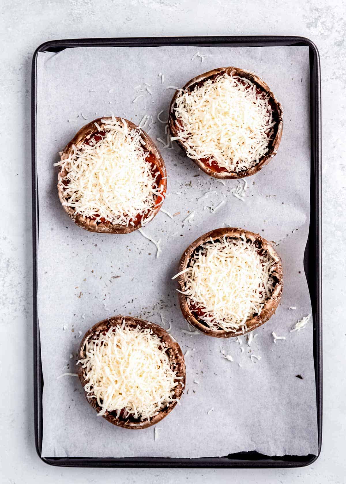 cheese being added to stuffed mushrooms 