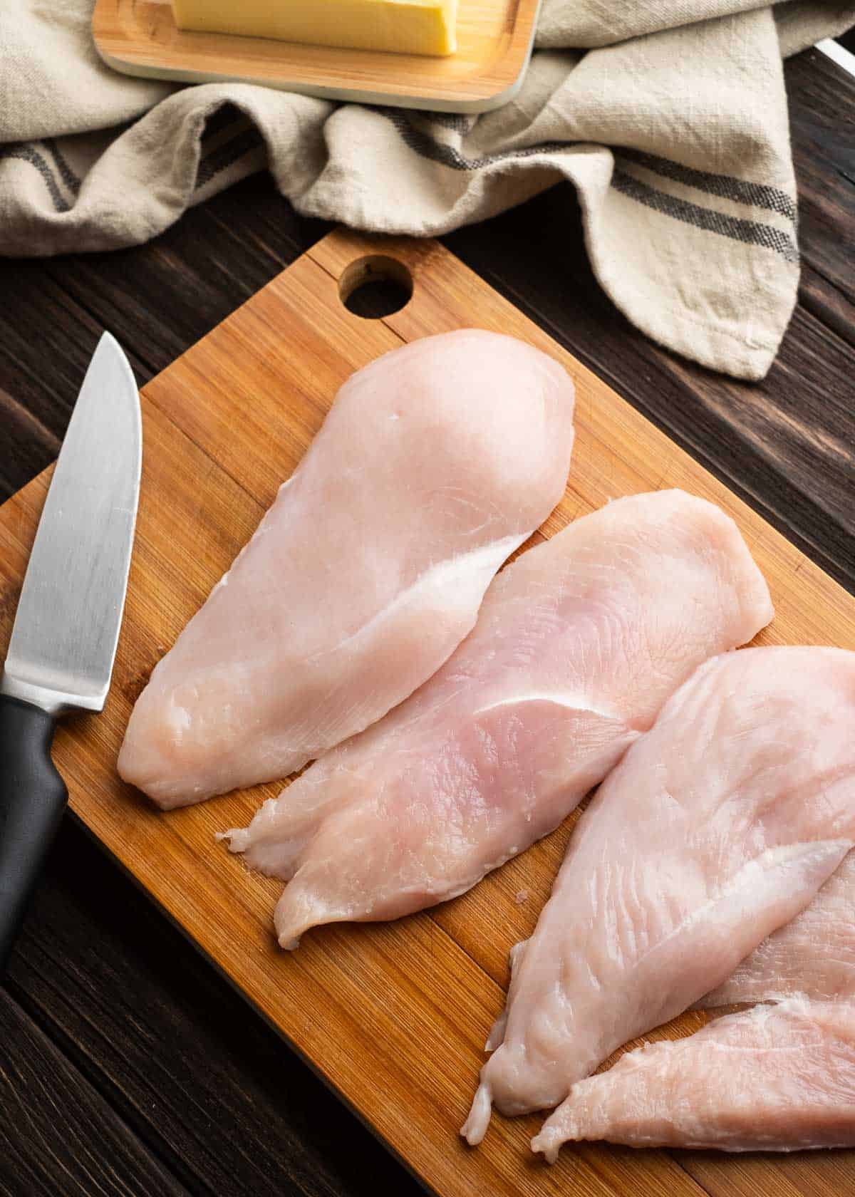 sliced chicken breasts on a wood cutting board