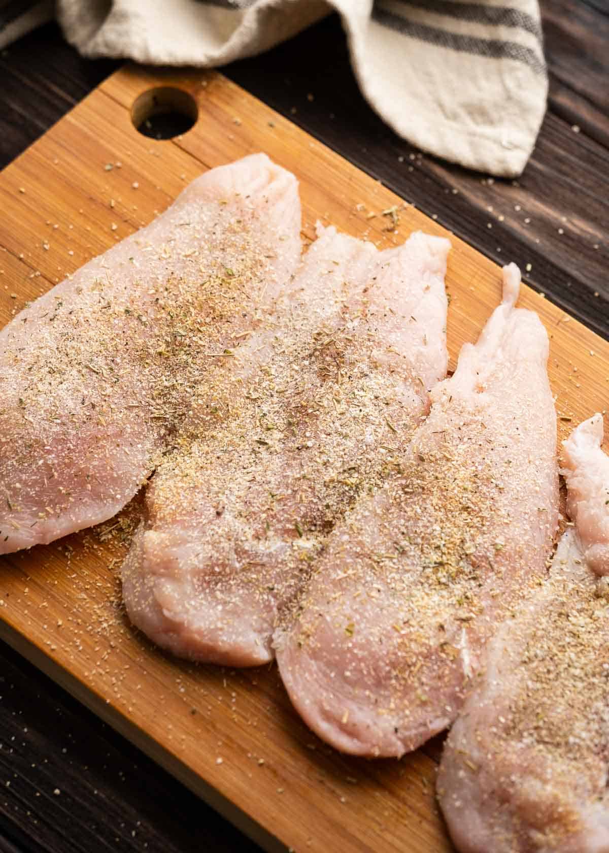 seasoned chicken breasts on a wooden cutting board