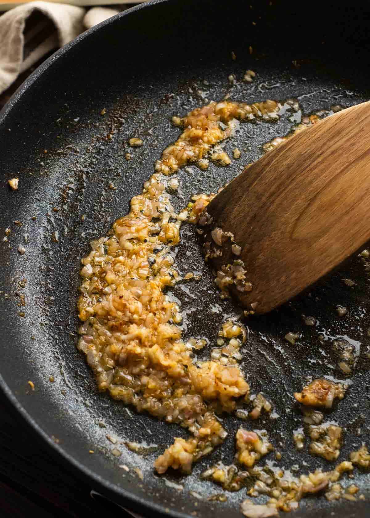 garlic and shallot being sauteed in cast iron skillet