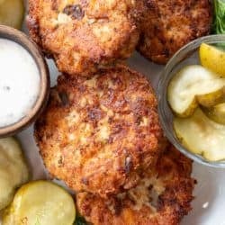 a plate with dill pickle chicken fritters, pickles, and dipping sauce