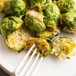 close up image of parmesan brussels sprouts and fork on a white plate