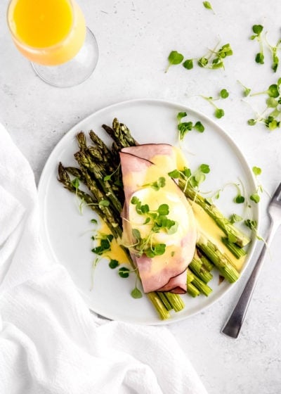 overhead image of asparagus eggs benedict assembled on a white plate