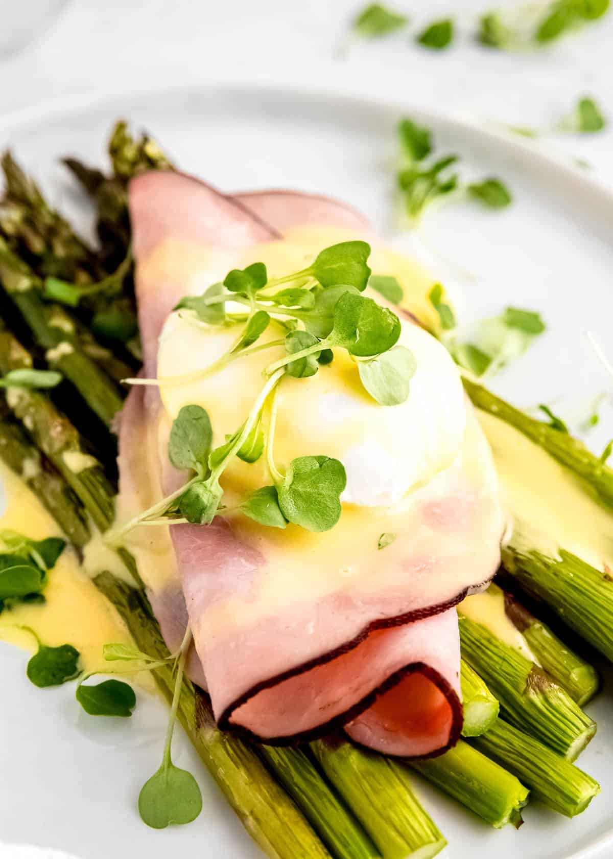 close up image of asparagus eggs benedict on a white plate