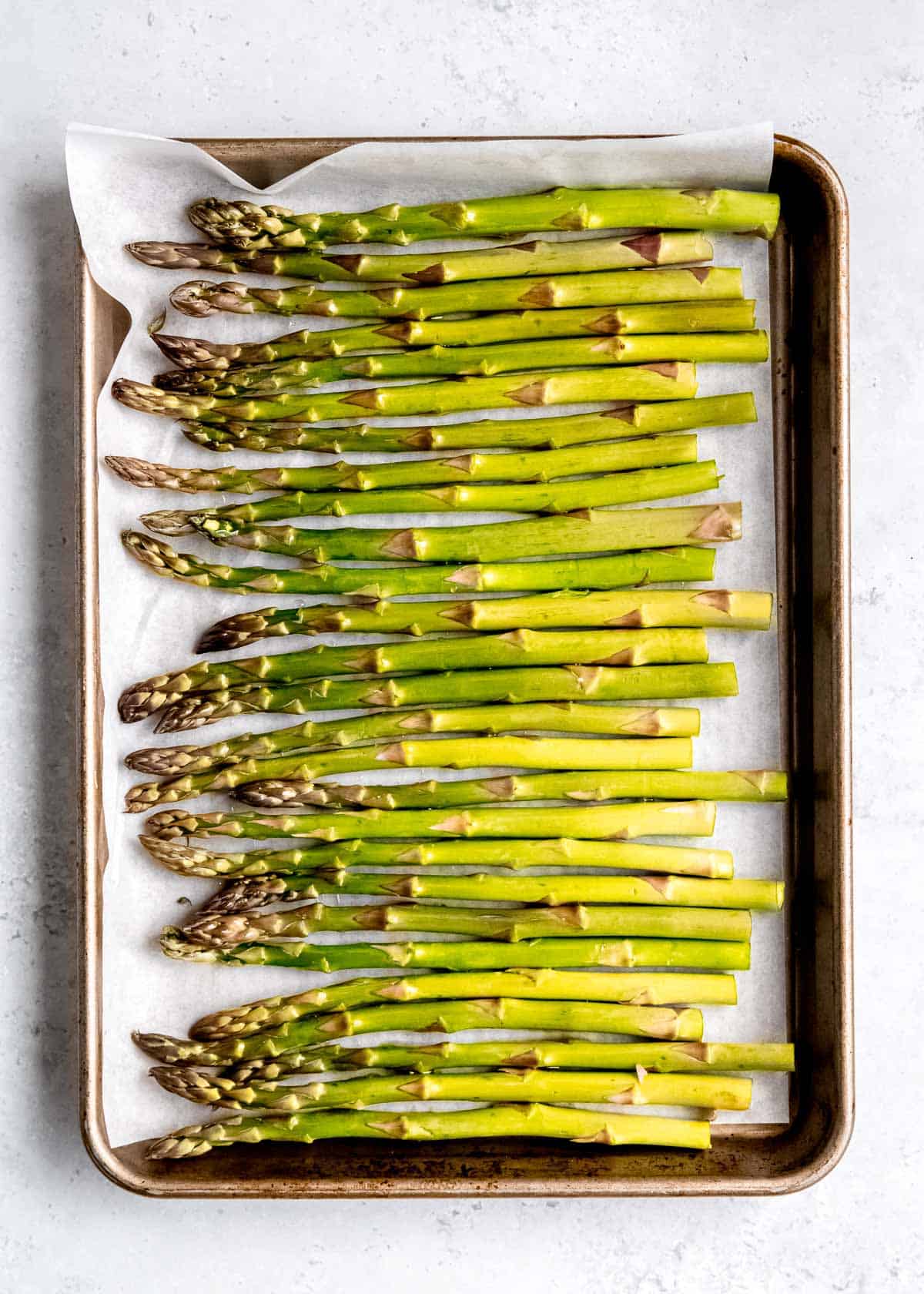 asparagus spread out on a baking sheet