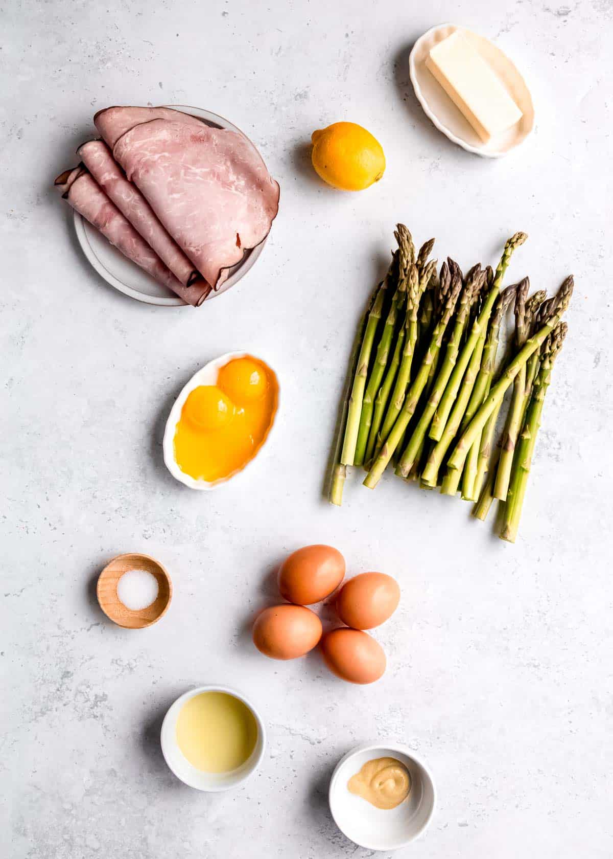 asparagus eggs benedict ingredients on a white table