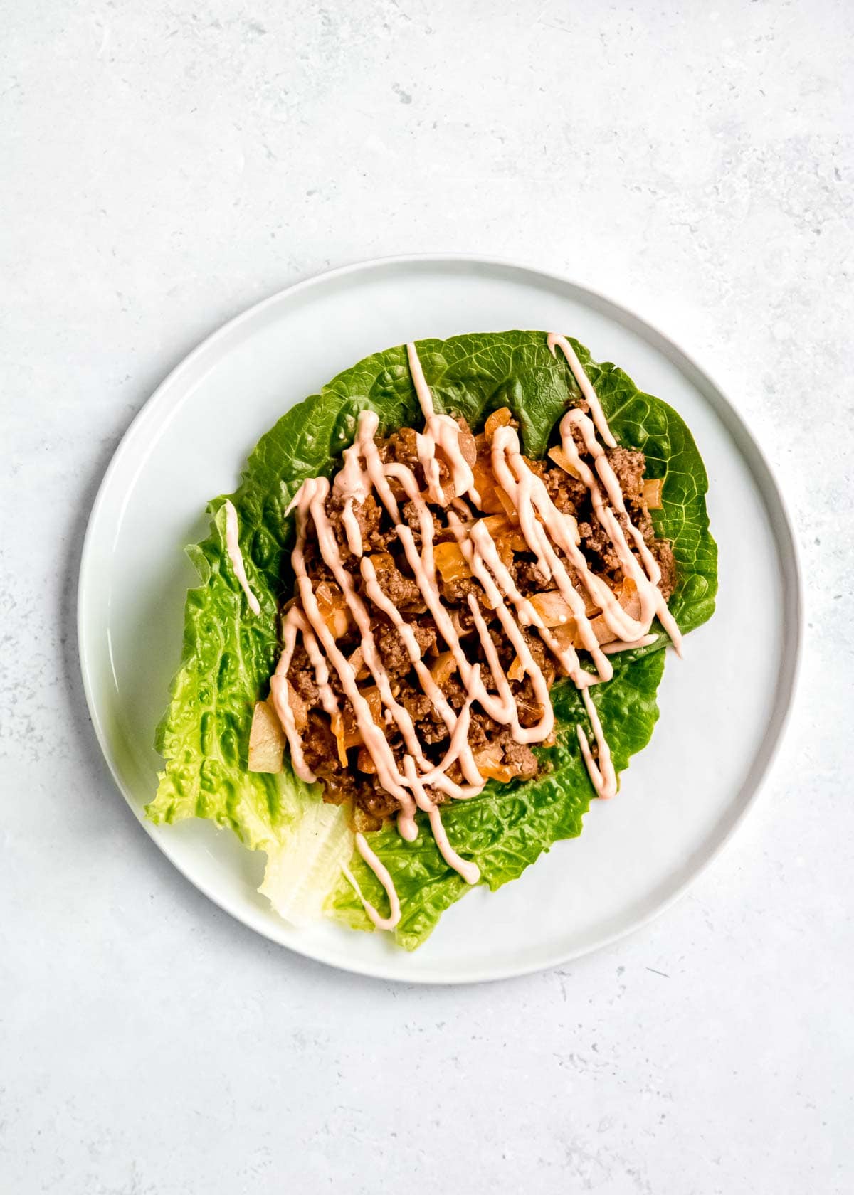 overhead image of sauce drizzled on lettuce wrap burger