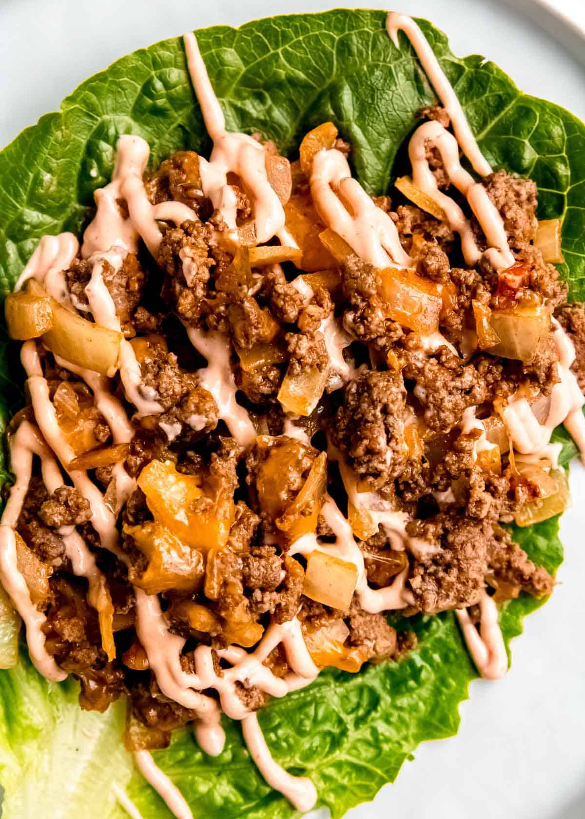 close up overhead image of a lettuce wrap burger with sauce drizzled on top
