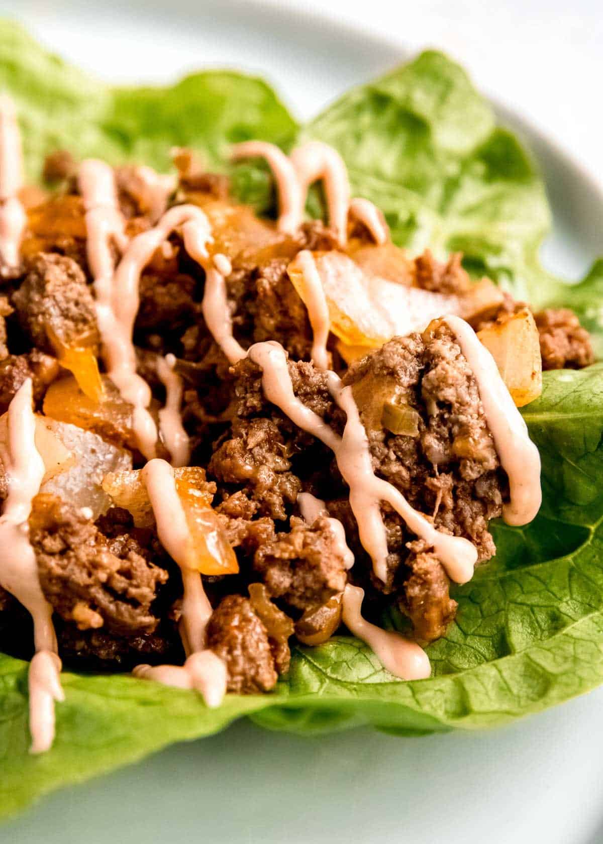close up image of lettuce wrap burger with sauce drizzled on top