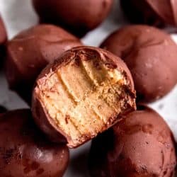 close up image of an espresso truffle with a bite taken out of it. Plate of truffles in background.