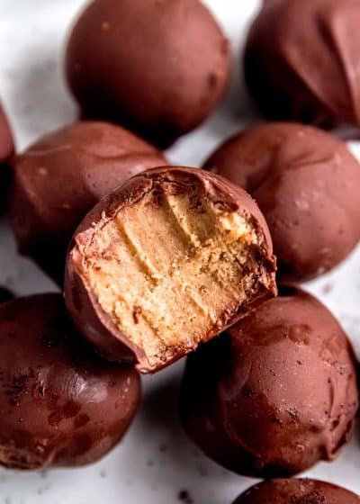 close up image of an espresso truffle with a bite taken out of it. Plate of truffles in background.