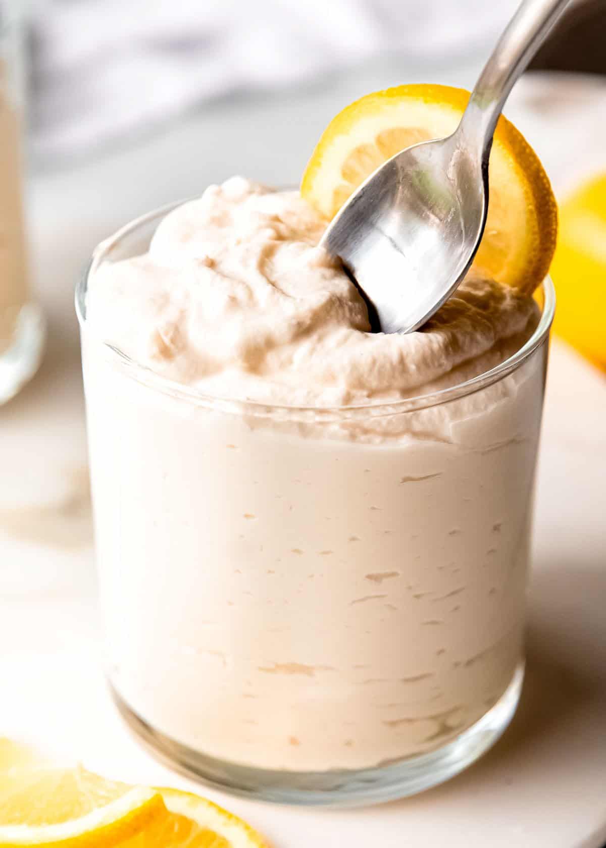 close up image of lemon mousse being spooned out of clear glass