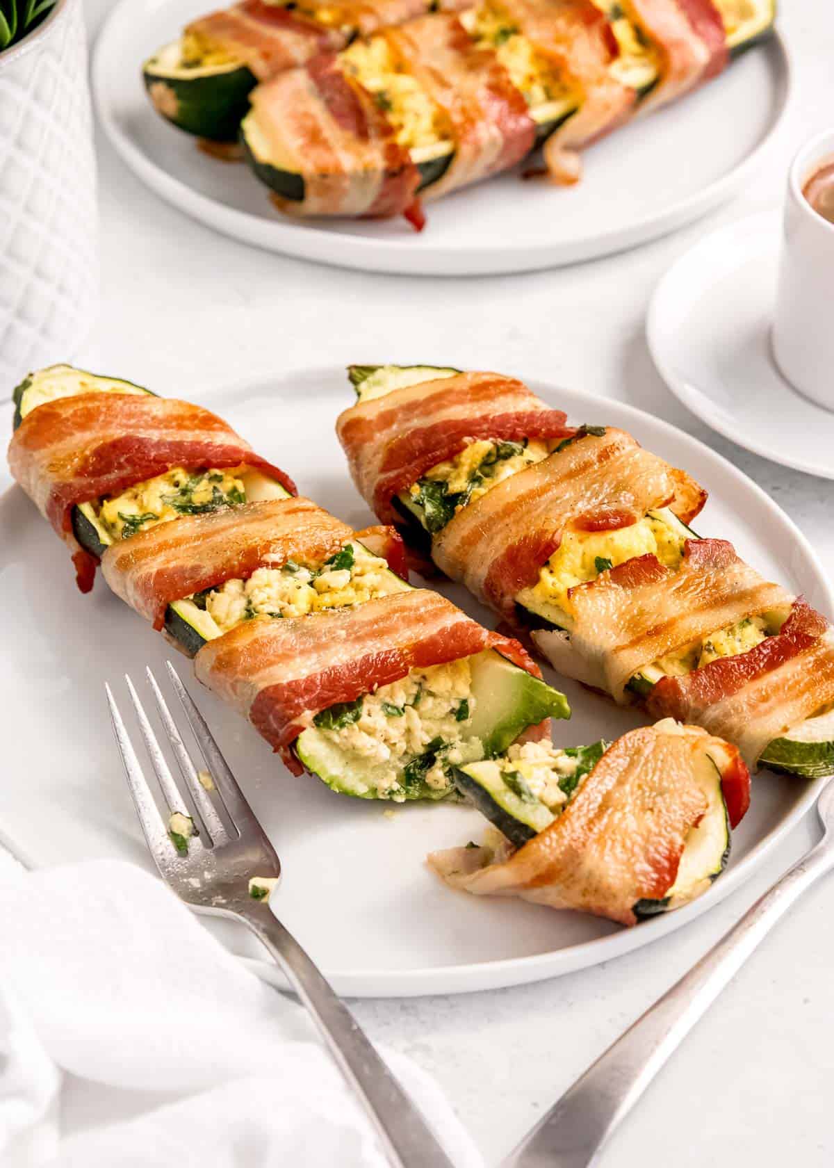 bacon wrapped zucchini boats on white plate 
