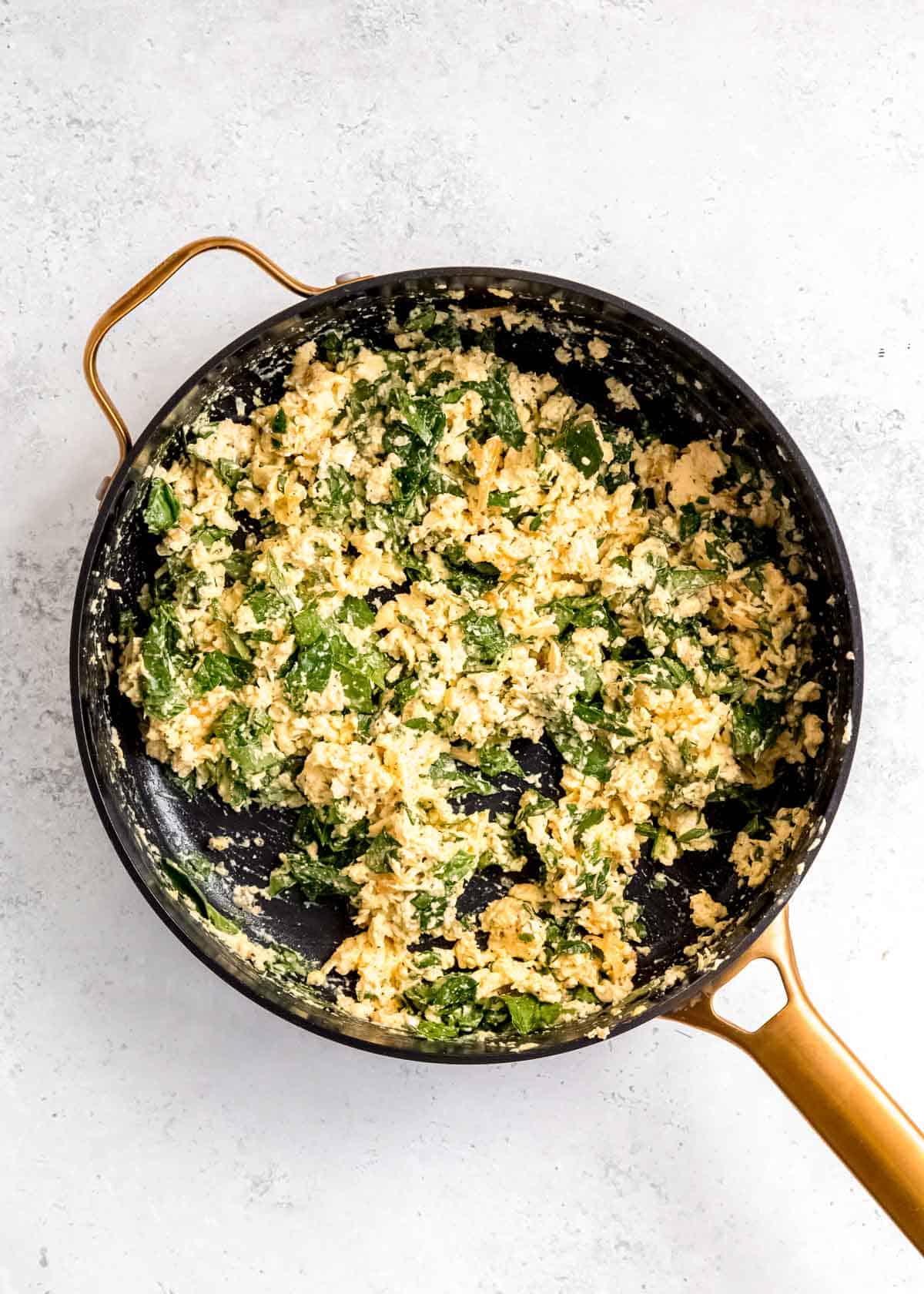 melted cheese over scrambled eggs and spinach