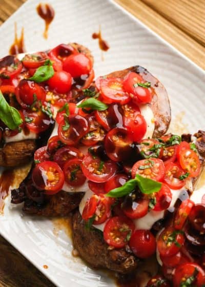 overhead image of bruschetta being added to chicken breasts on white plate