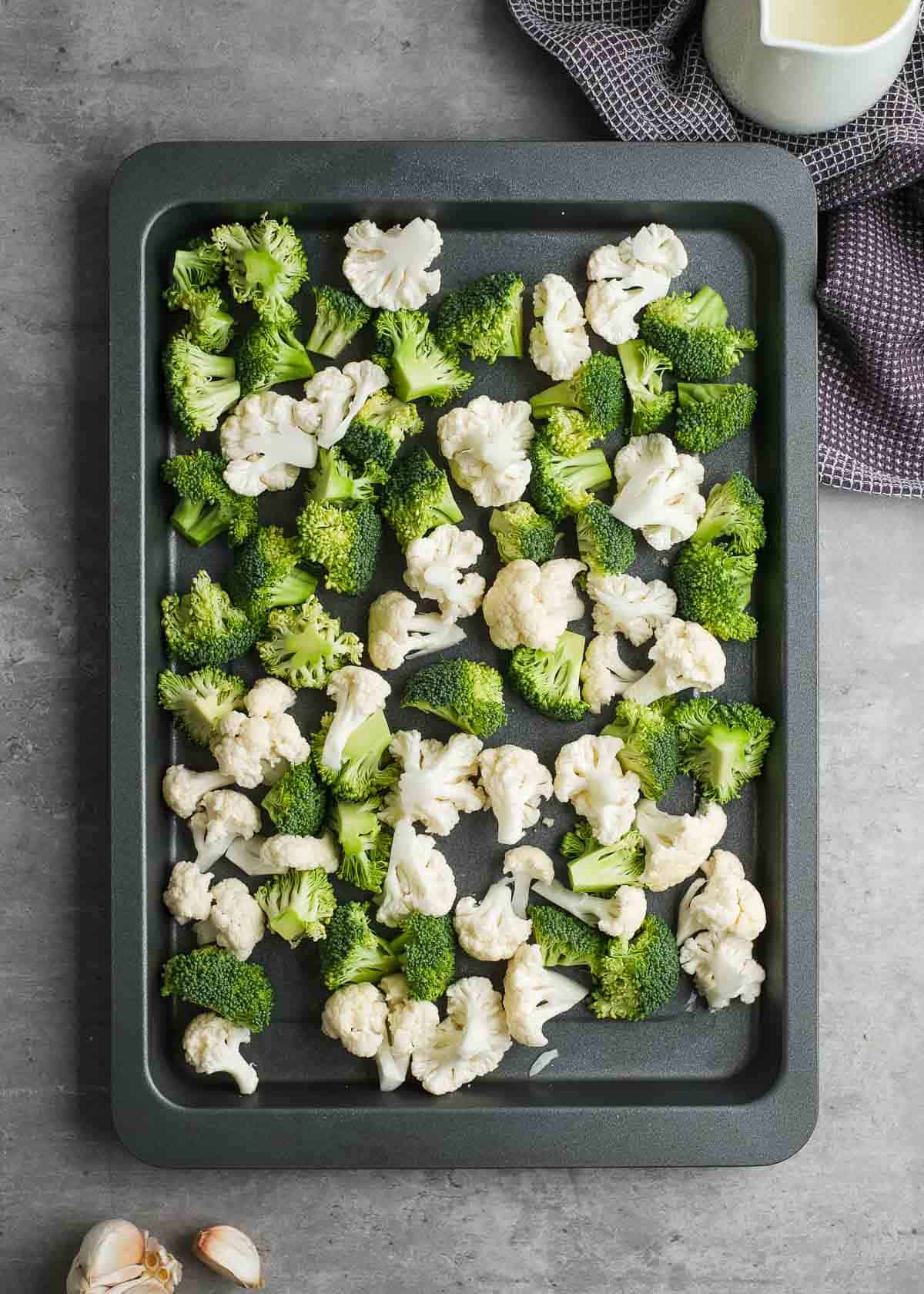 cauliflower and broccoli florets on a greased baking dish