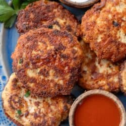 close up, overhead image of cheesy chicken fritters on a blue plate