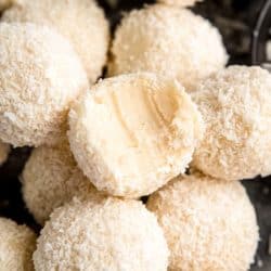 stack of coconut truffles with a bite removed from one coconut truffle