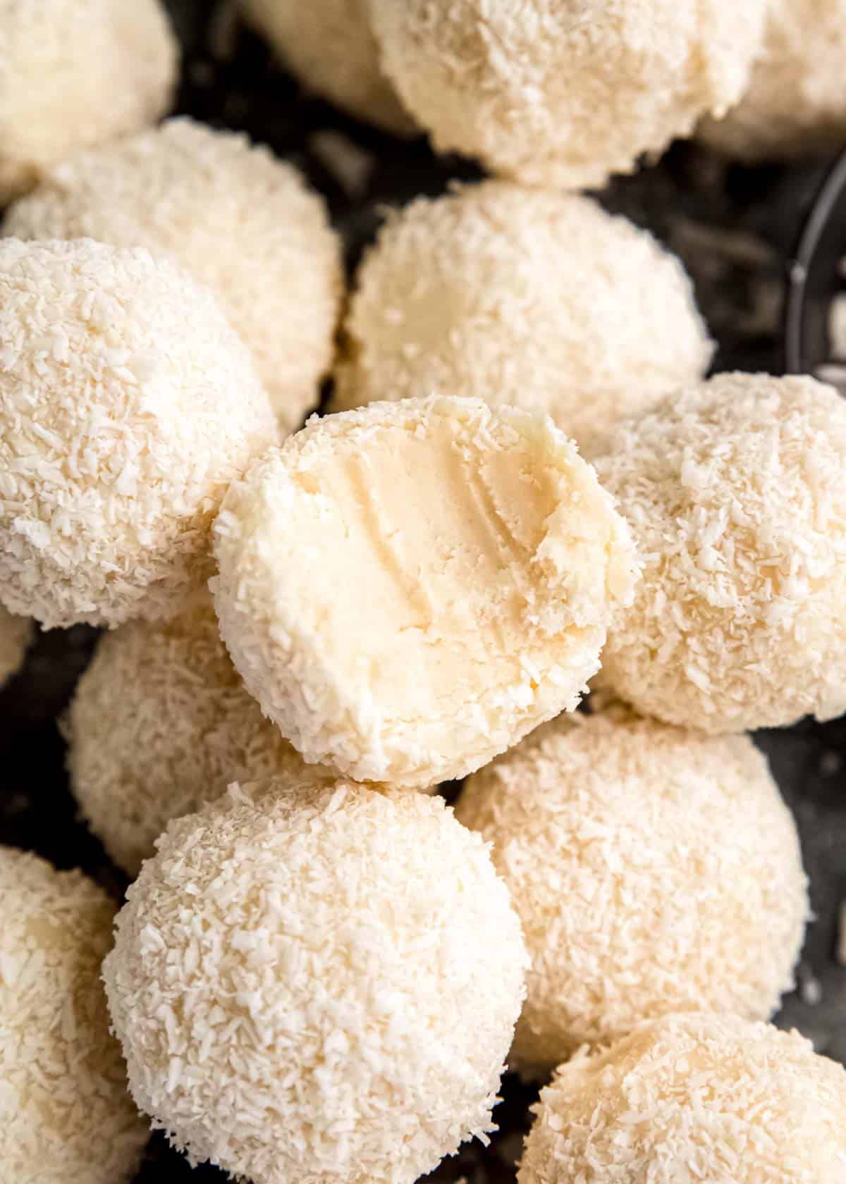 stack of coconut truffles with a bite removed from one coconut truffle