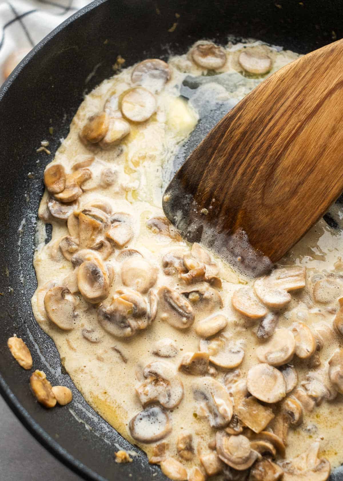 creamy mushroom chicken sauce being thickened in cast iron skillet