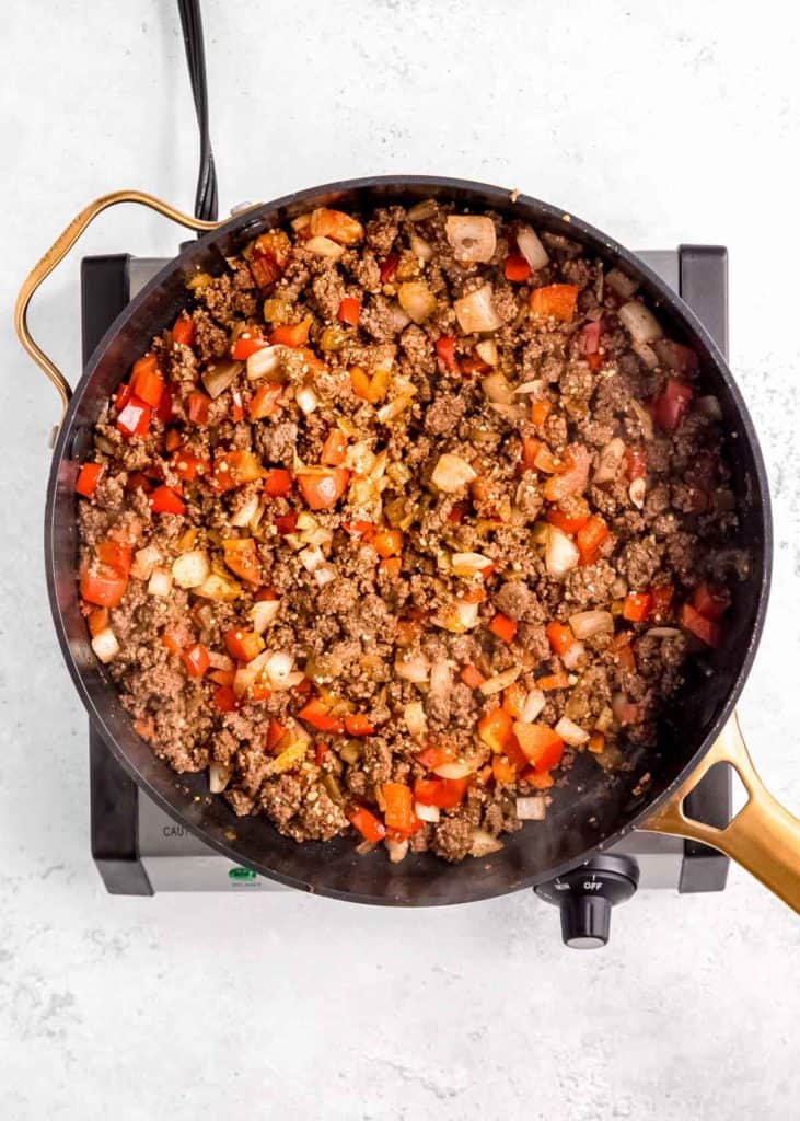 sauteed veggies mixed in with seasoned beef in a skillet