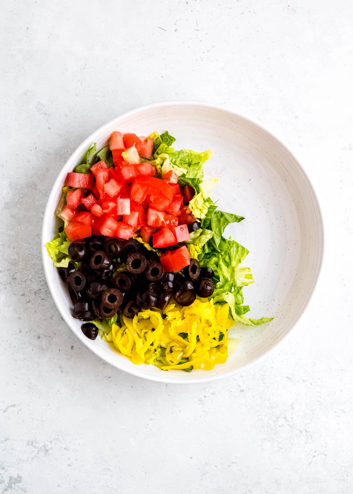 step 1 of adding italian sub in a tub ingredients to white bowl on white table