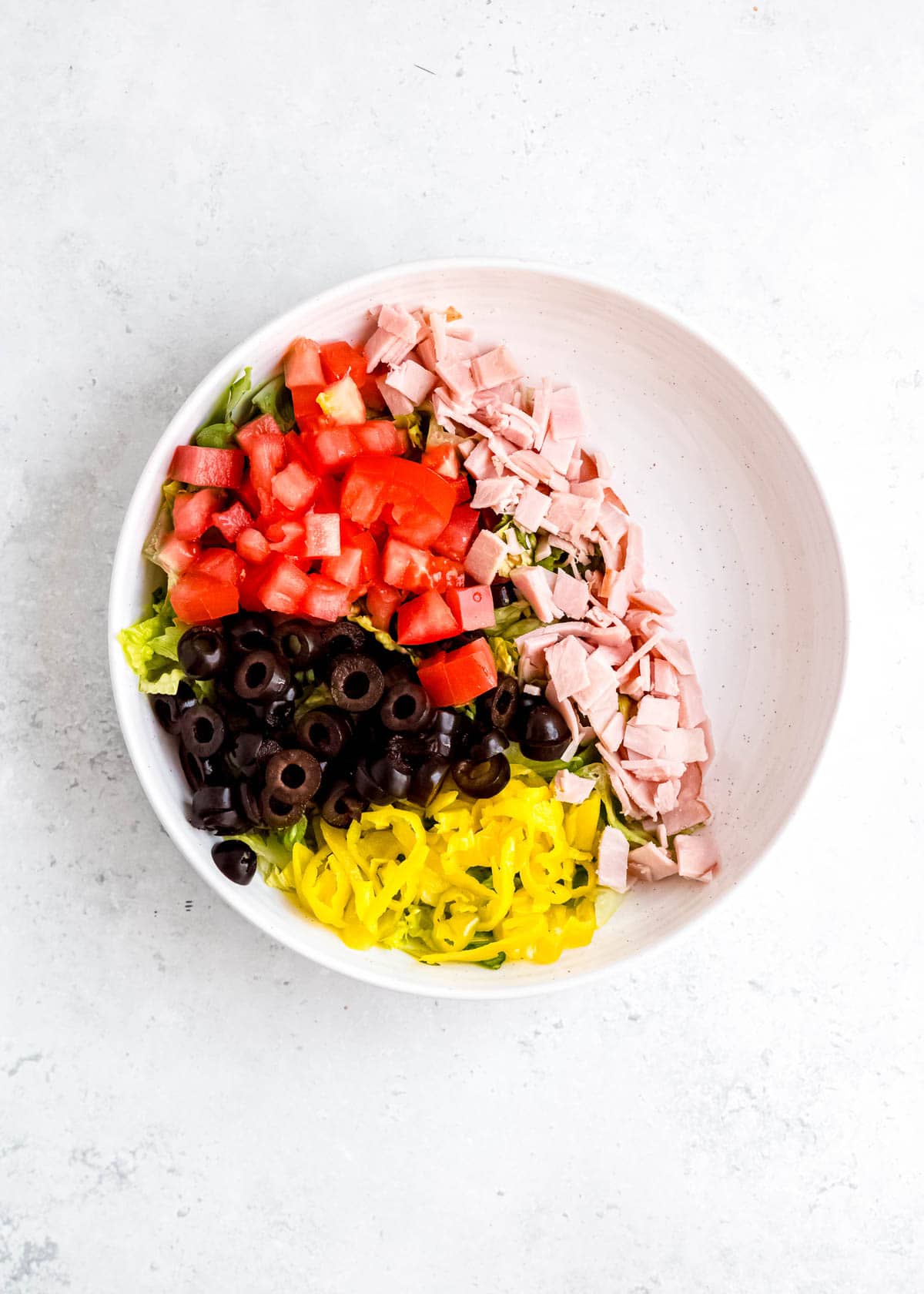 step 2 of adding italian sub in a tub ingredients to white bowl on white table