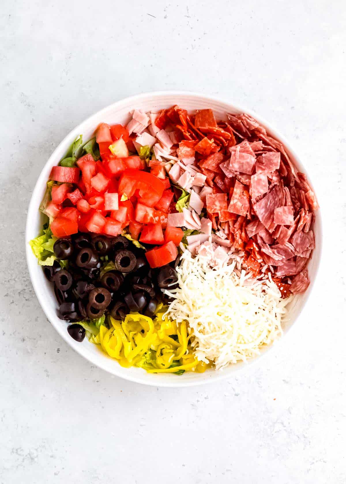 step 5 of adding italian sub in a tub ingredients to white bowl on white table