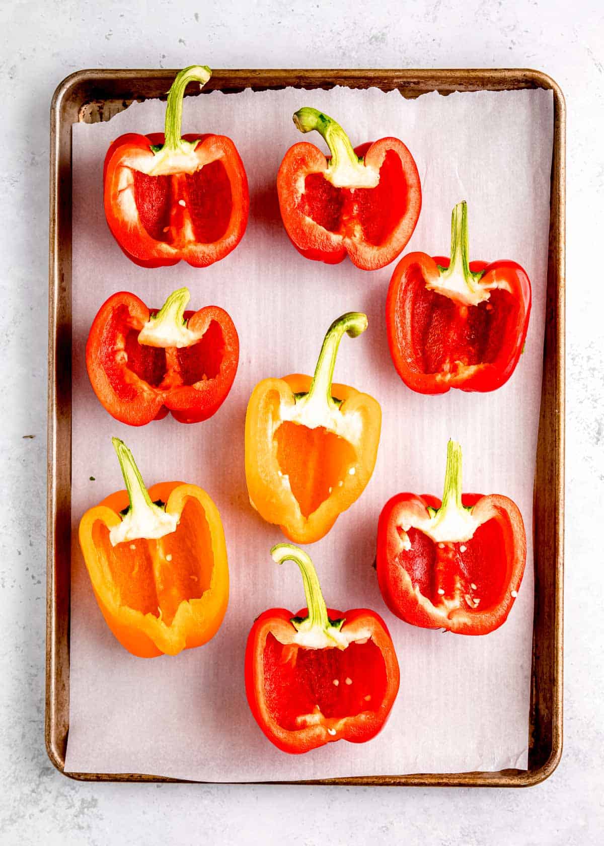 halved bell peppers on lined baking sheet