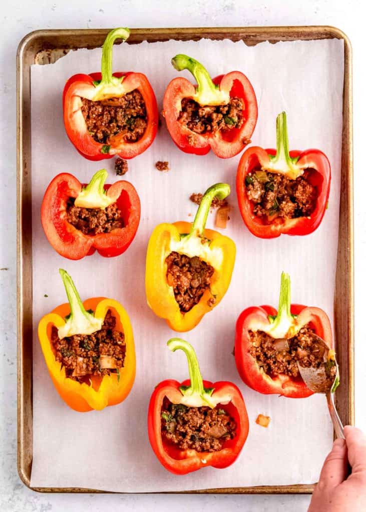 meat filling being added to lasagna stuffed peppers on baking sheet