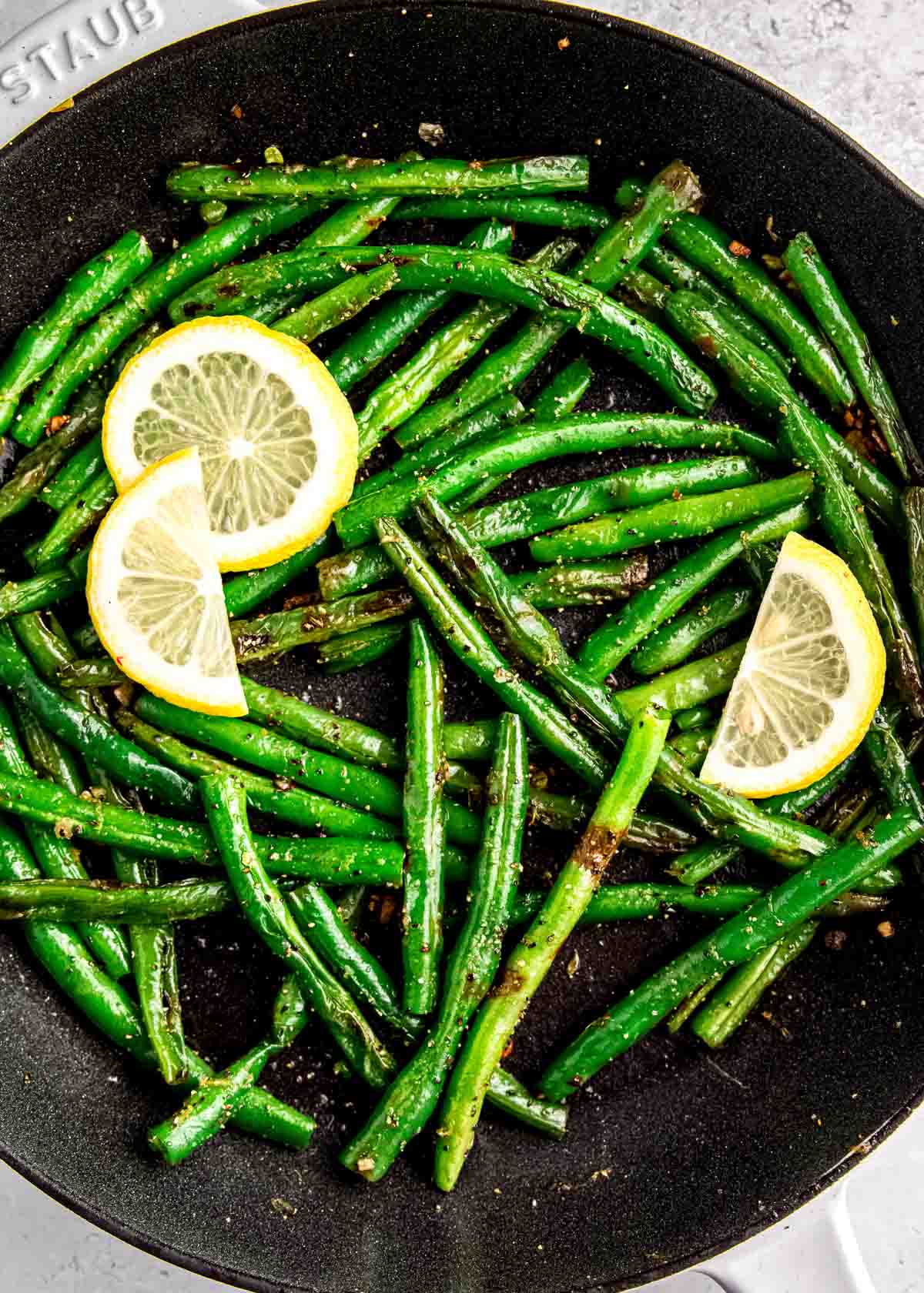 overhead image of lemon pepper green beans and lemon slices