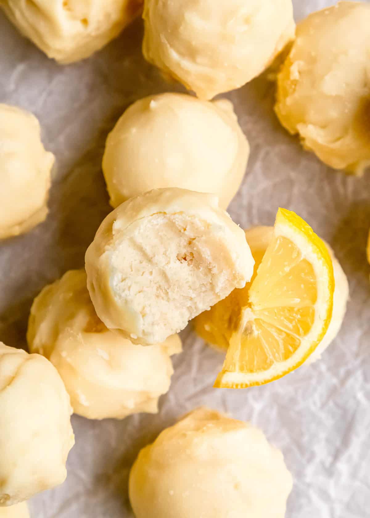 close up image of a lemon truffle with a bite taken out of it stacked on other truffles