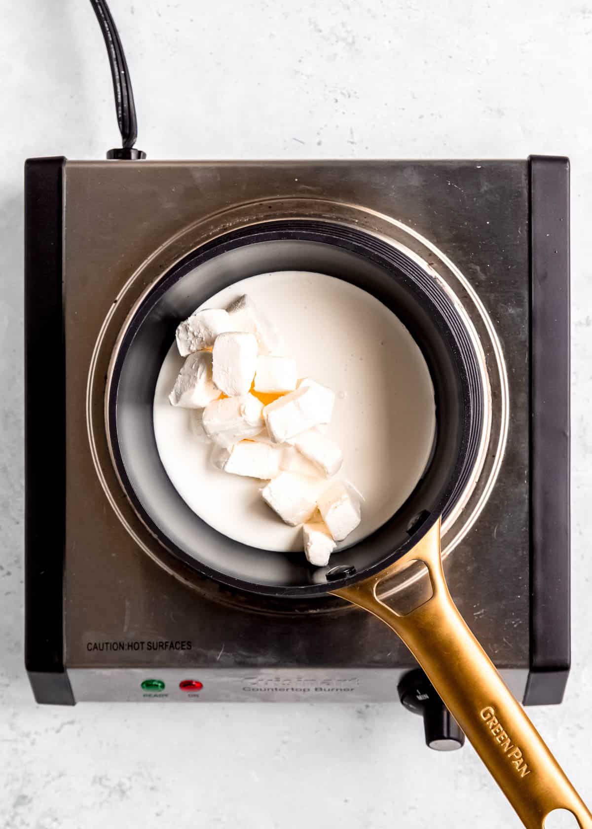 overhead image of cream cheese being added to saucepan