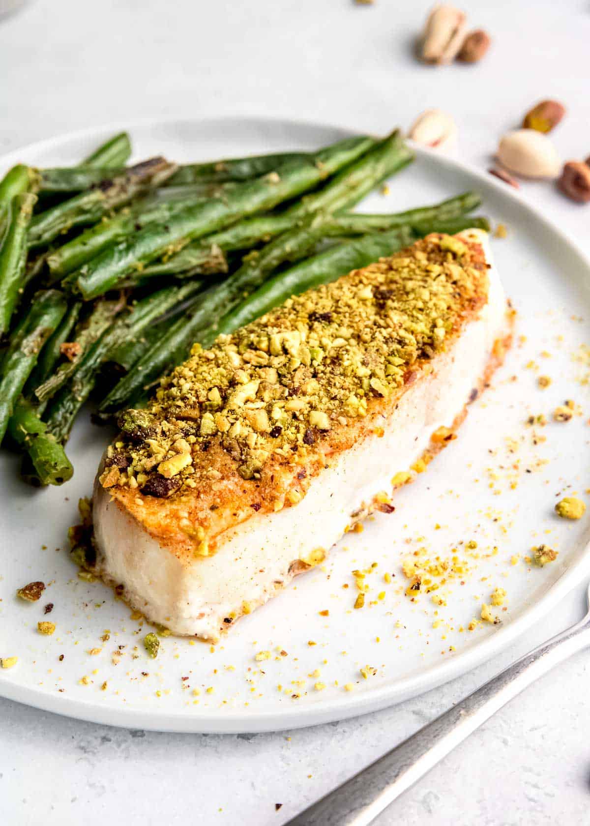close up, angled image of pistachio crusted halibut on white plate