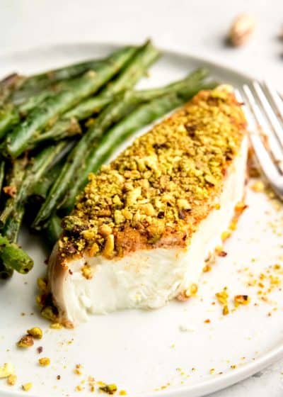 pistachio crusted halibut and beans on white plate