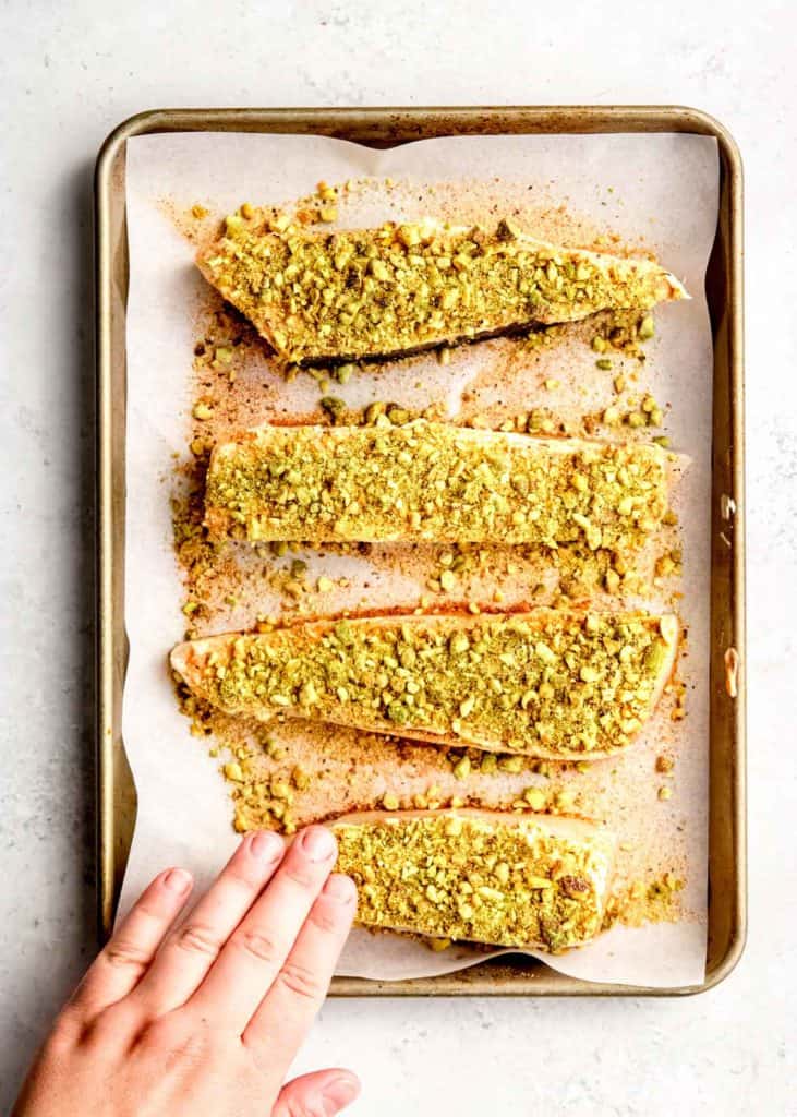 pistachios being patted into filets to ensure adhesion
