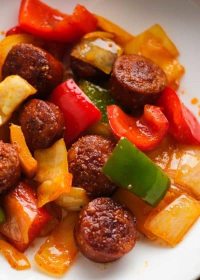 close up image of sausage and peppers with cabbage in white bowl