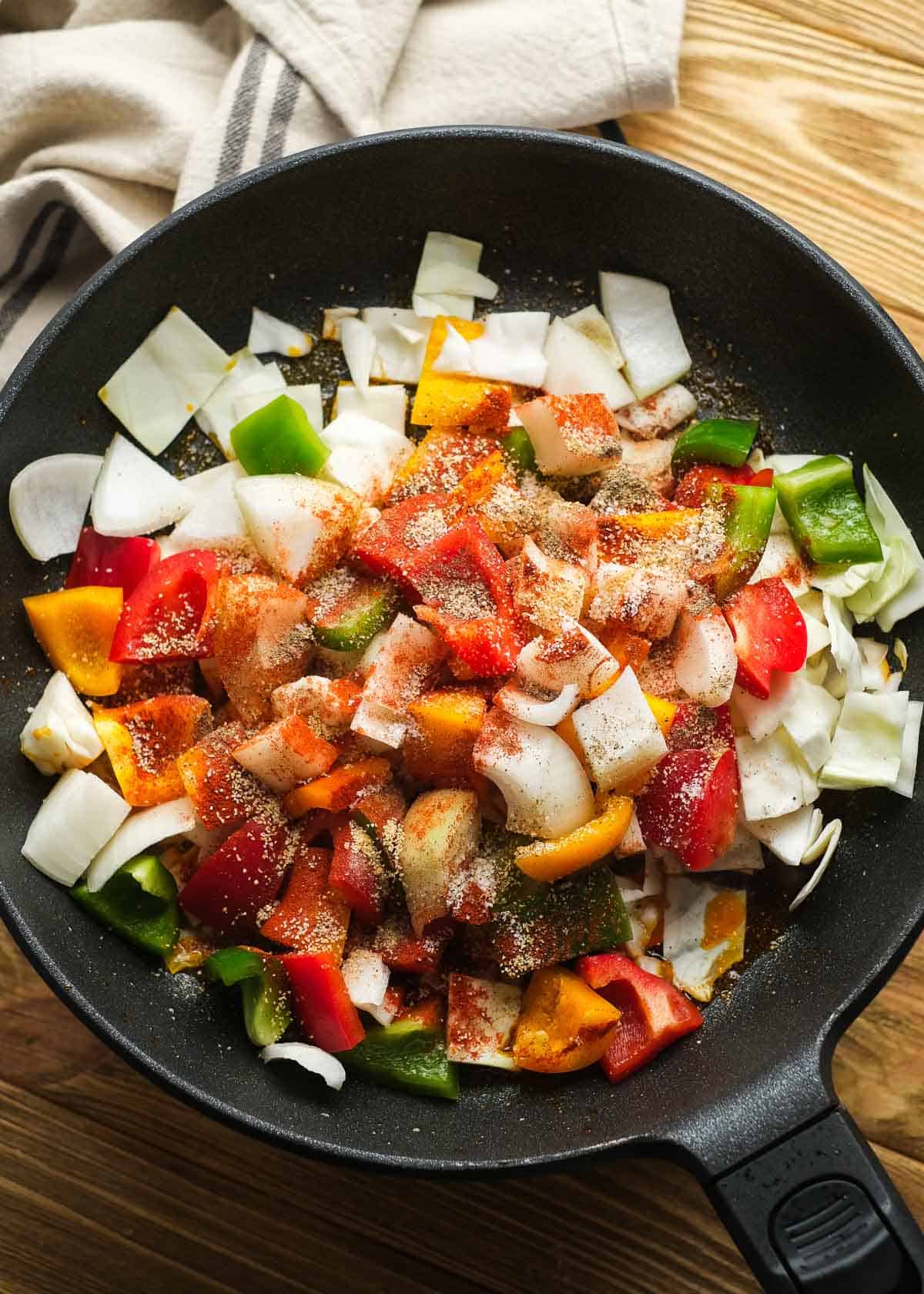 sausage and peppers with cabbage being cooked in cast iron skillet