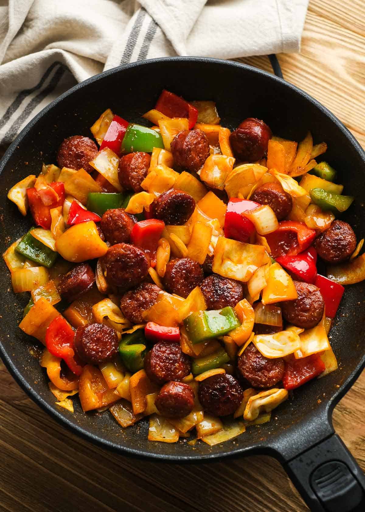 cooked sausage and peppers with cabbage in cast iron skillet