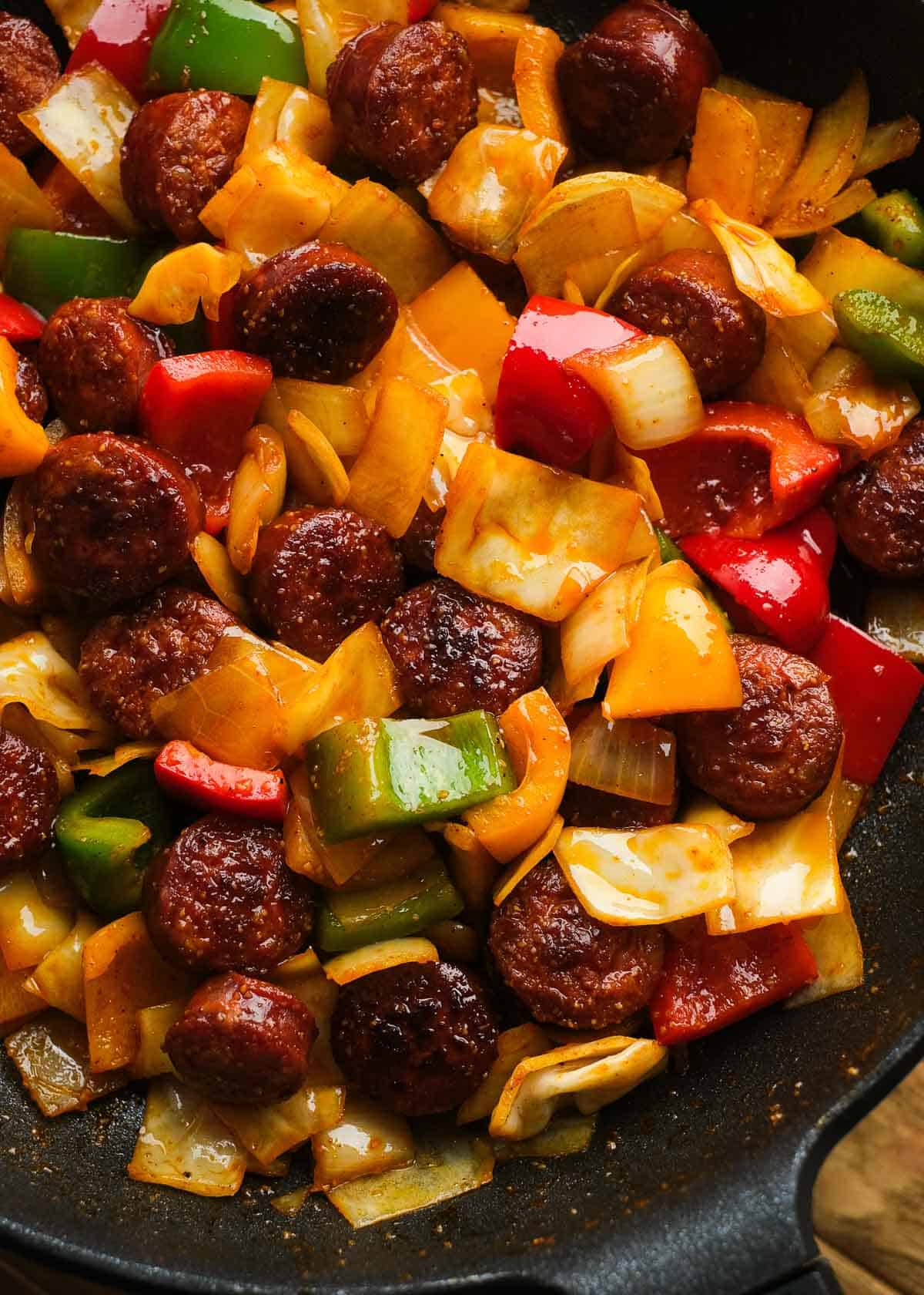 close up image of sausage and peppers with cabbage in a cast iron skillet