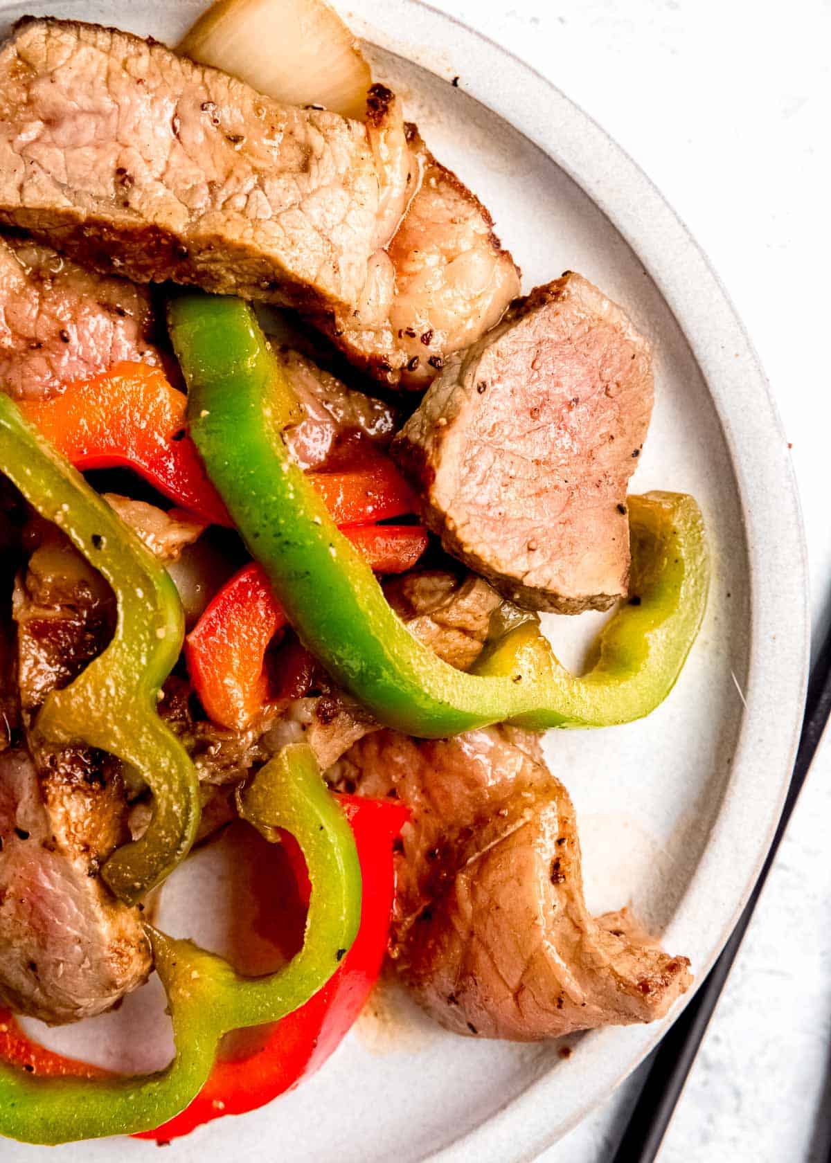 close up image of skillet pepper steak on white plate