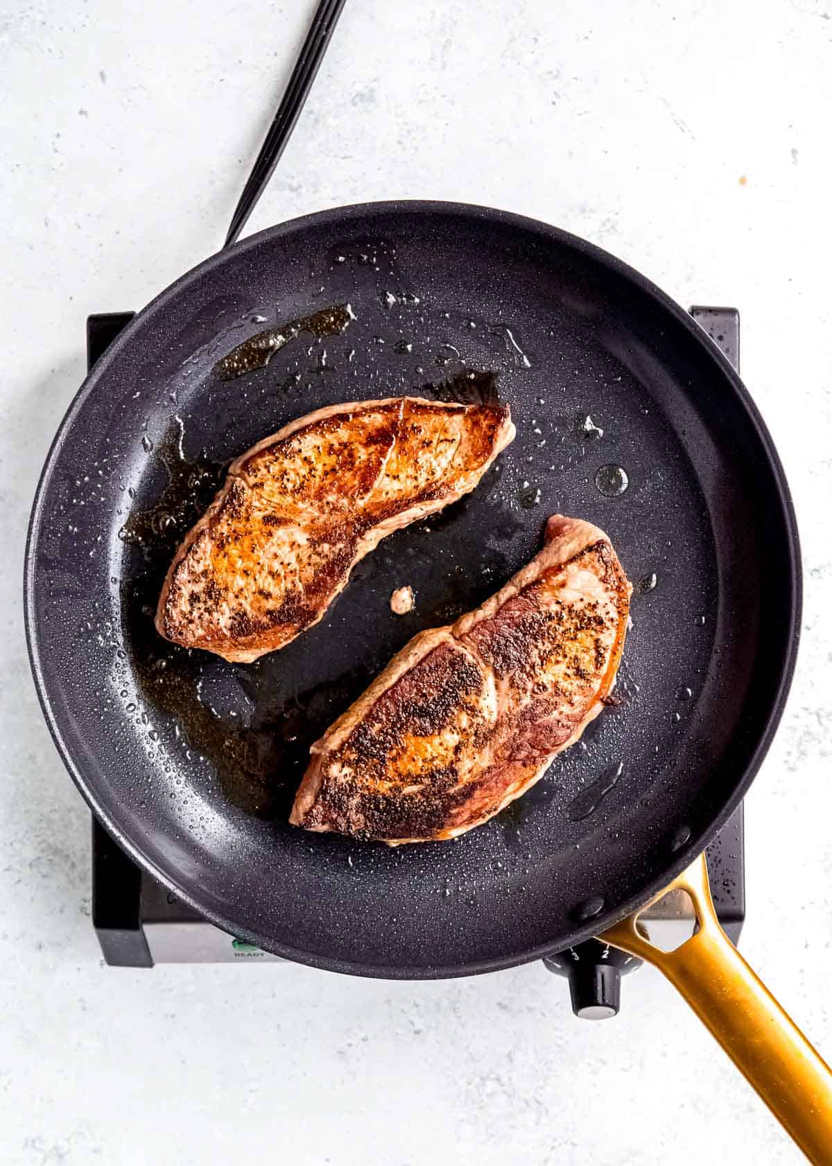 steak being seared in skillet